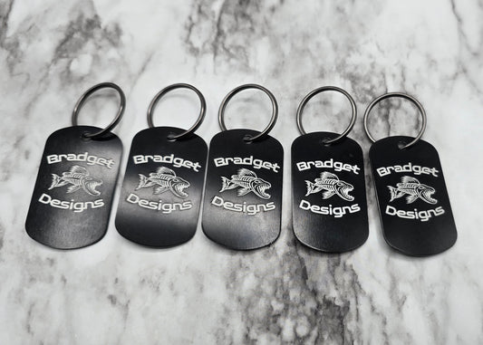 Set of five black keychains with 'Bradget Designs' logo on a marble surface