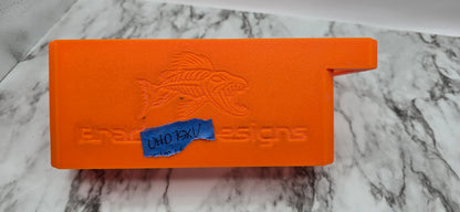 Orange tool with a fish design and 'Bradget Designs' branding on a marble surface