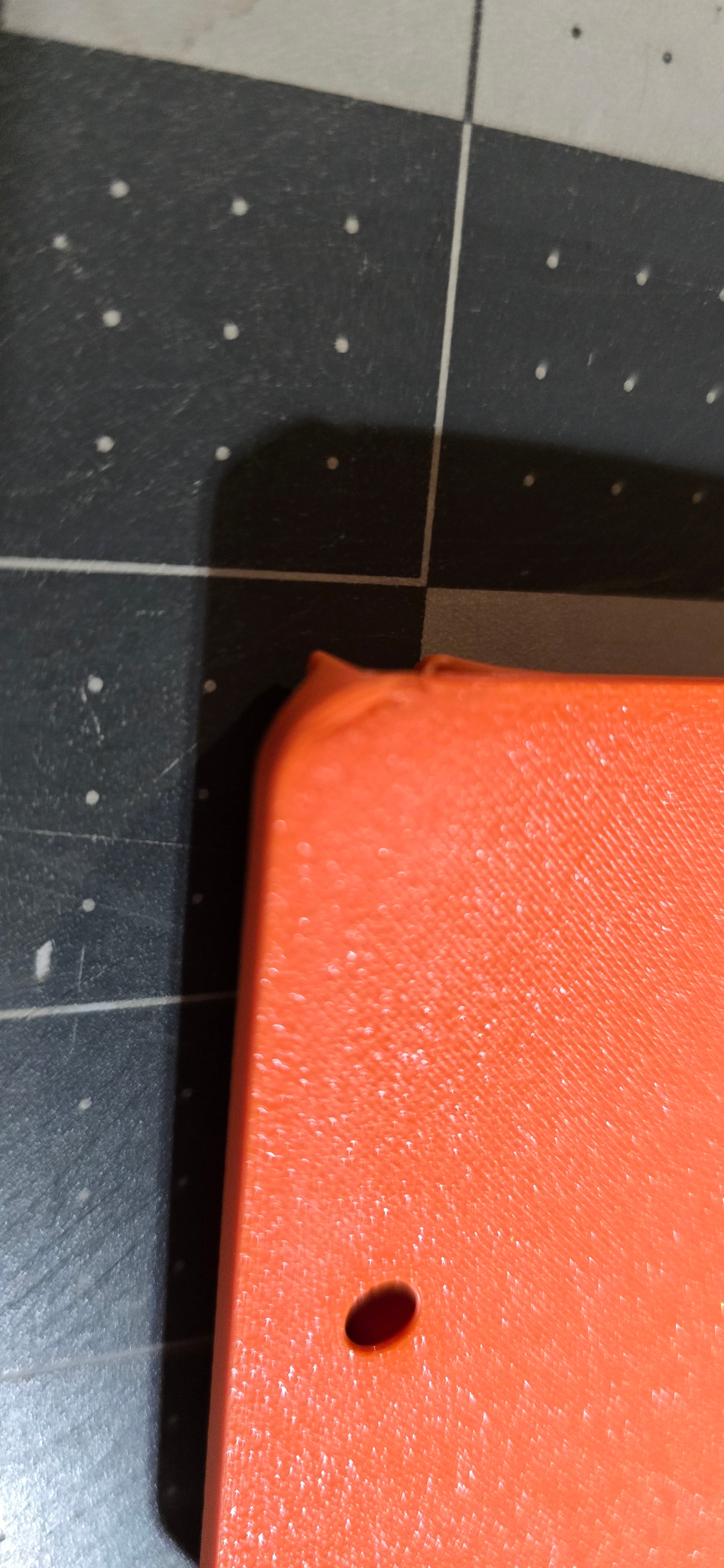 Close-up of a blemished slot mount on a tiled floor