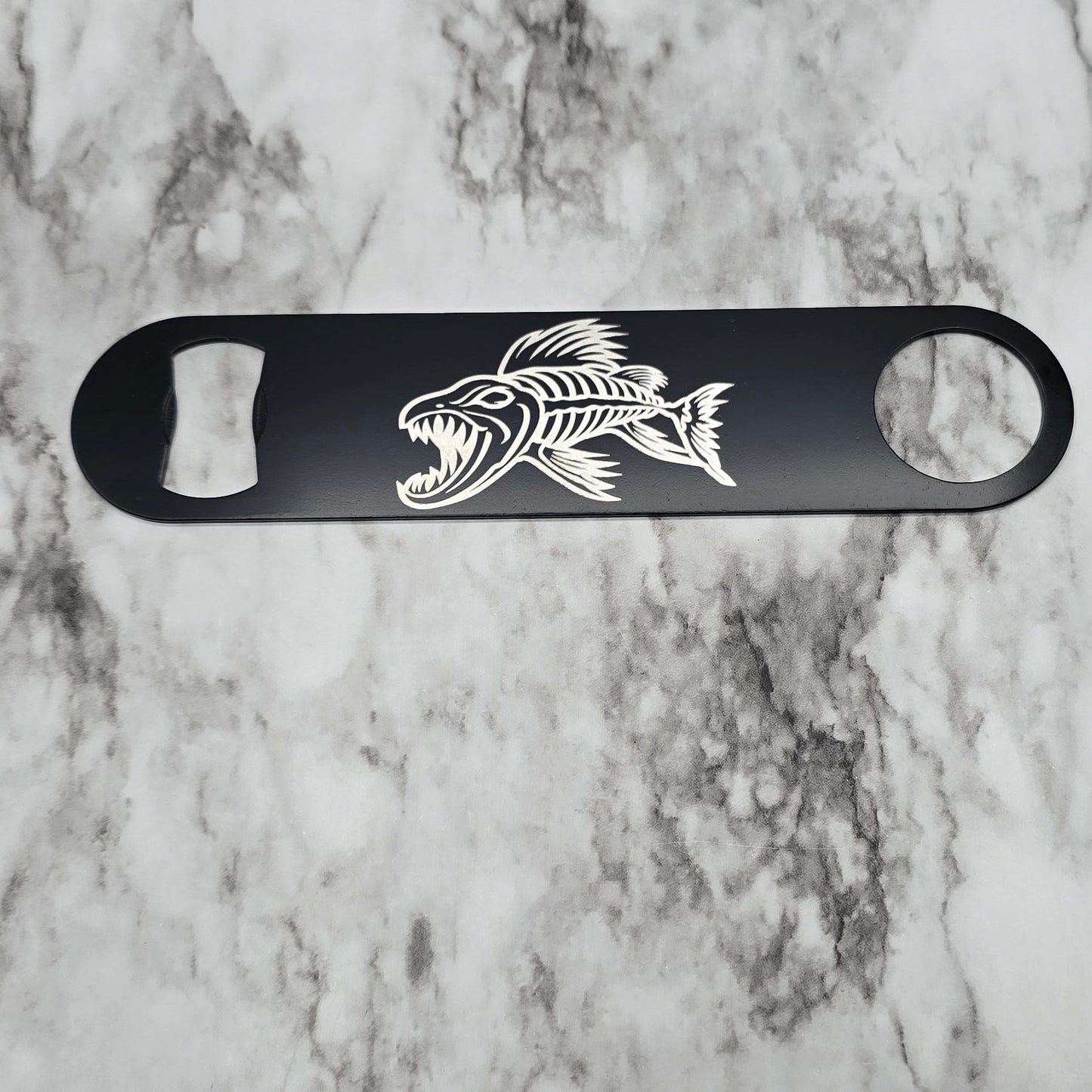 Black bottle opener with a fish design on a marble surface