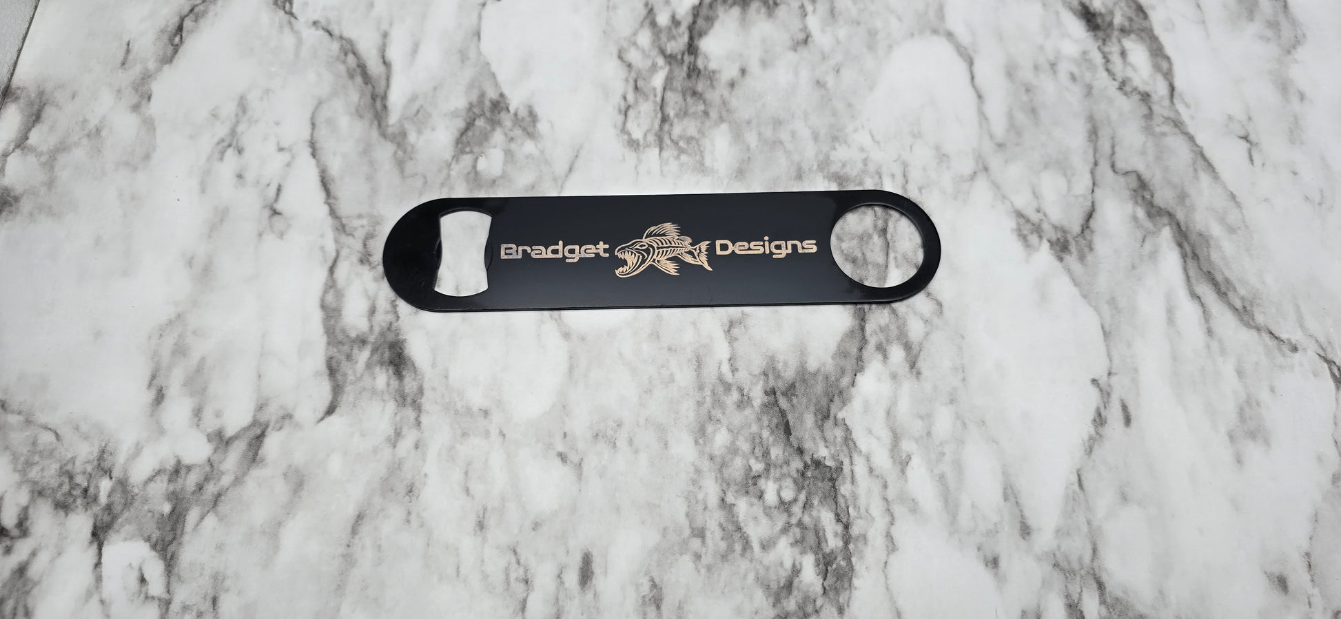 Black bottle opener with branding on a marble surface