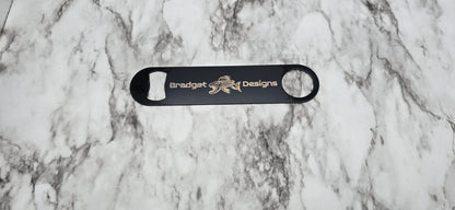 Black bottle opener with branding on a marble surface